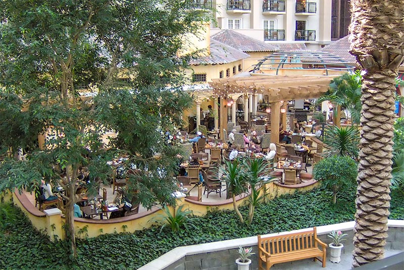 A view from above of people eating on a leafy Orlando patio with string lights