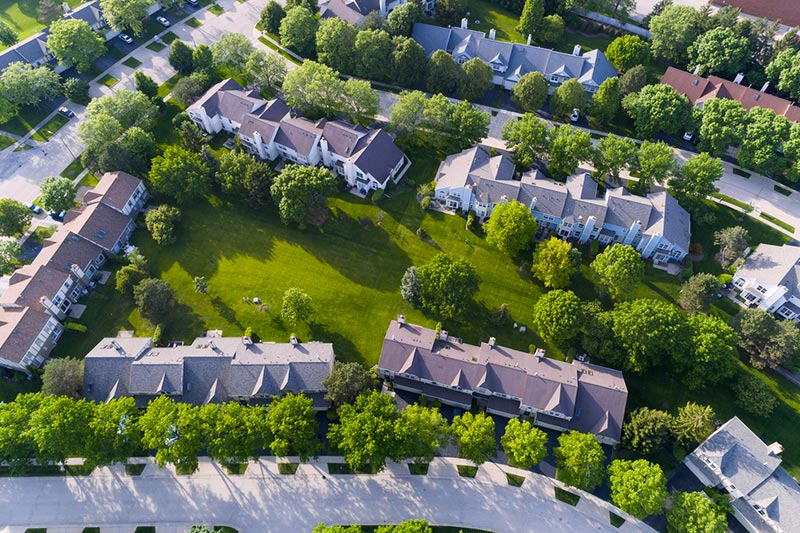Aerial view of townhome community with green grass in between.