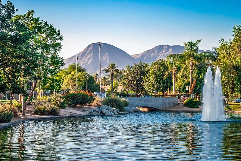A pond and bridge surrounded by palm trees and a mountain behind them in Palm Springs California