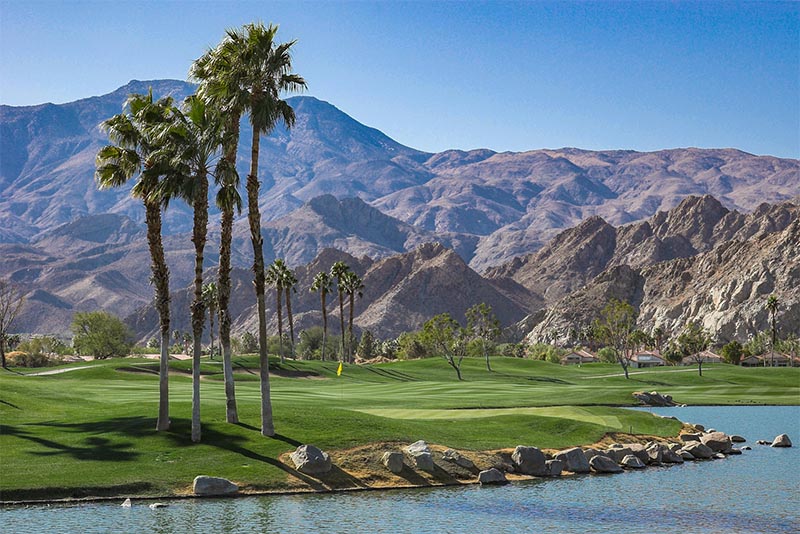 A golf course surrounded by palm trees with a mountain backdrop in Palm Springs
