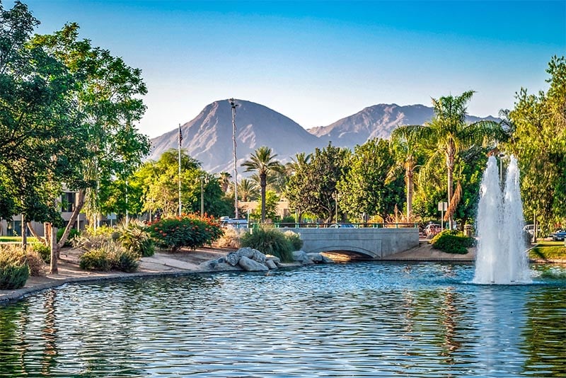 A pond with palm trees around it in front of a mountain backdrop in Palm Springs
