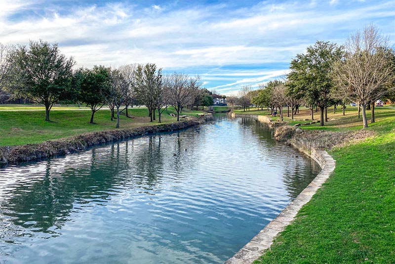 A pond surrounded by trees in a park in Plano, Texas