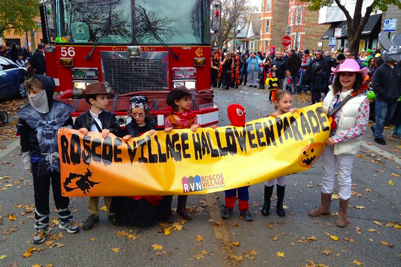 Dressed up children holding sign for Roscoe Village NEighbors Halloween Parade and Party.