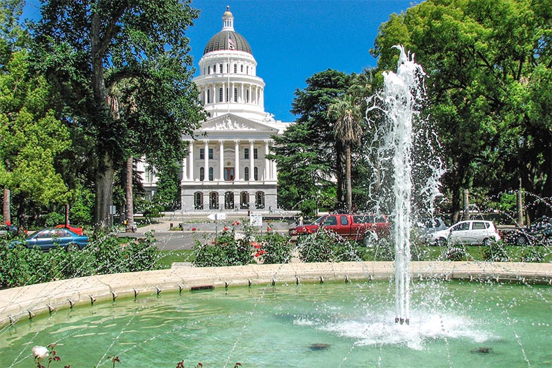 A view of the California Capitol building in Sacramento from near a fountain in front of it