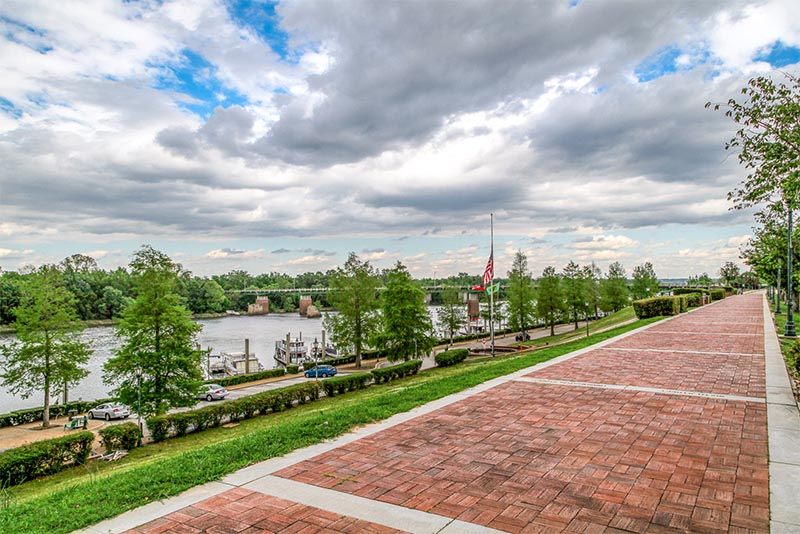 A scenic path along a river where you can see boats parked in Savannah Georgia