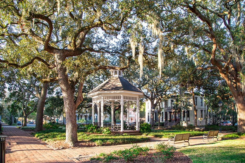 A gazebo sits at the center of a small Savannah park surrounded by Spanish moss