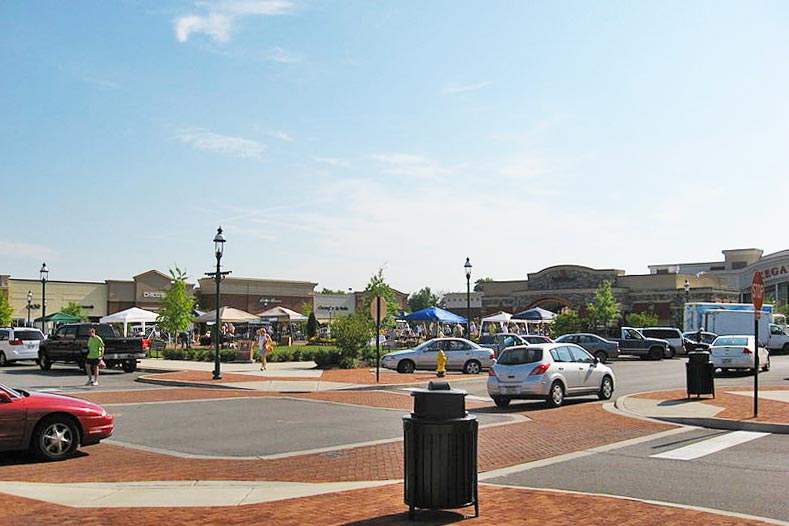 View of shopping center with people and cars in parking lot