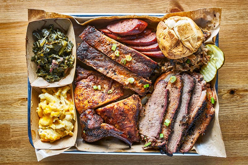A plate of Texas barbecue with hot links, ribs, and other barbecue foods