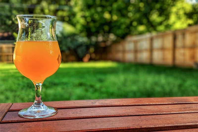 An orange-colored beer in a flute glass on a wooden table in Indiana