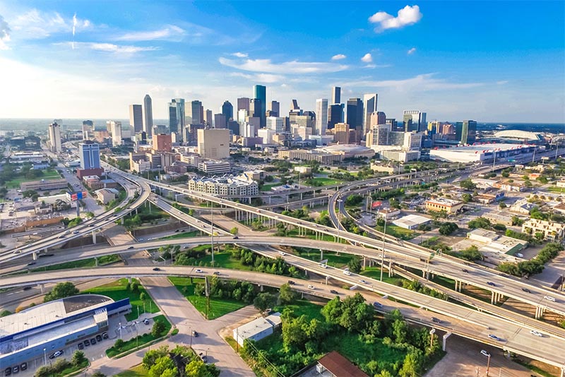 The Dallas skyline against a blue sky with a tangle of highways low in front of it