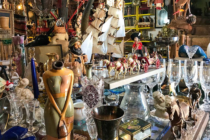 A dense image of many antiques stacked together on a table at an antique shop