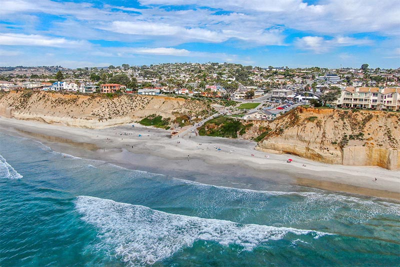 A view of the shore from out in the ocean of cliffs and buildings in San Diego