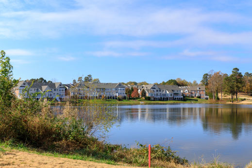 Pond and forest with homes along water.