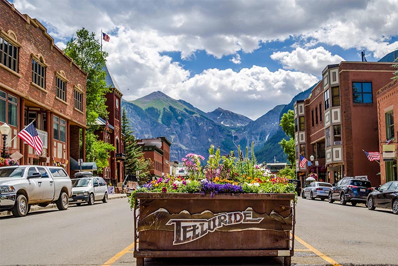A flower box that says Telluride in the middle of a street with a mountain in the background