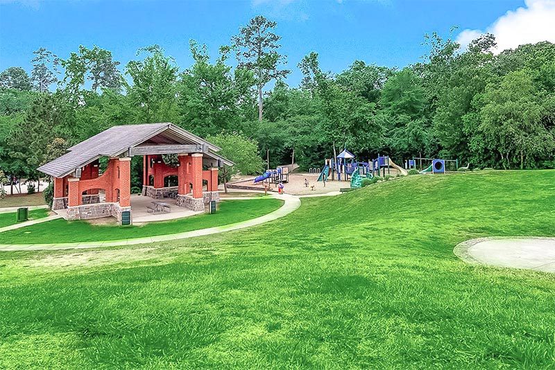 Looking down from a hill there is playground equipment and a picnic pavilion