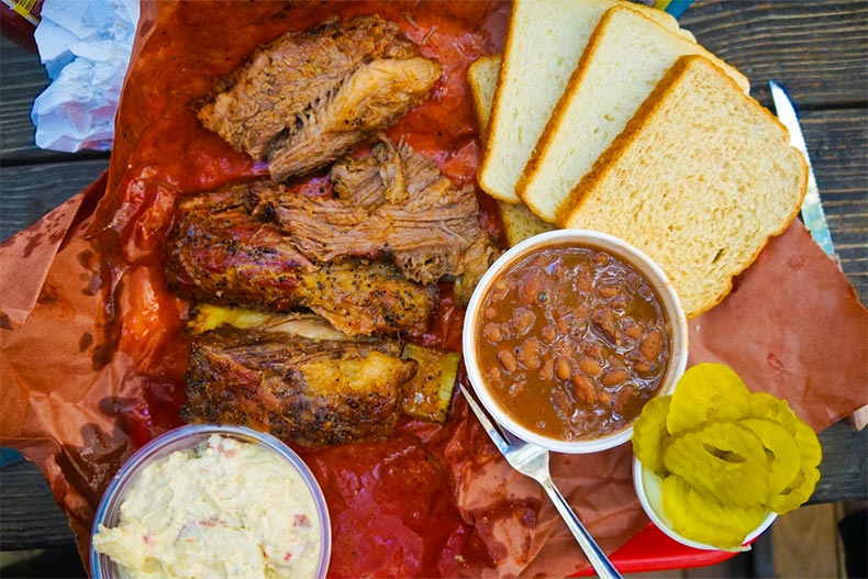 Texas BBQ with beans, bread, and pickles on a plate