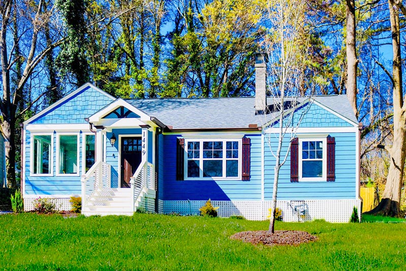 Exterior of colorful house with trees in background.