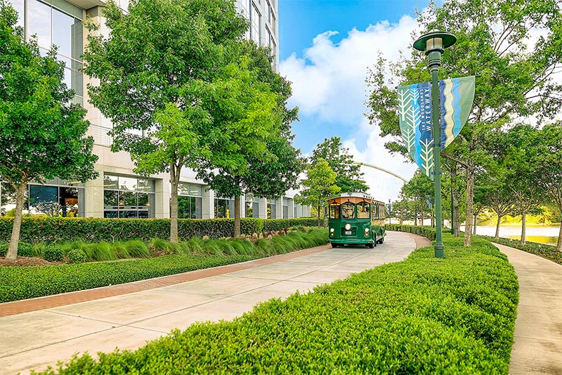 The Woodlands Trolley driving down a tree-lined street