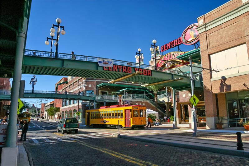 View of neighborhood street with pedestrian bridge and yellow tour bus.